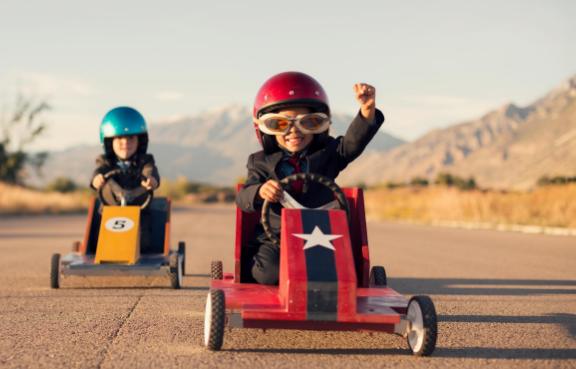 Zwei Kinder fahren ein Seifenkistenrennen.