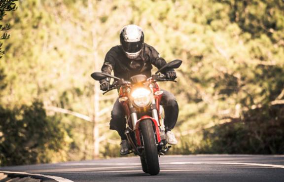 Ein Motorradfahrer fährt auf einer bewaldeten Landstraße.