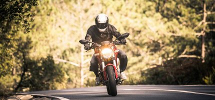 Ein Motorradfahrer fährt auf einer bewaldeten Landstraße.