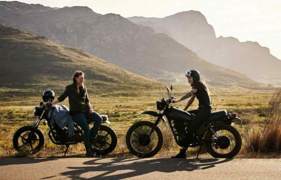 Zwei Motorradfahrer machen vor ein paar Hügeln Pause.