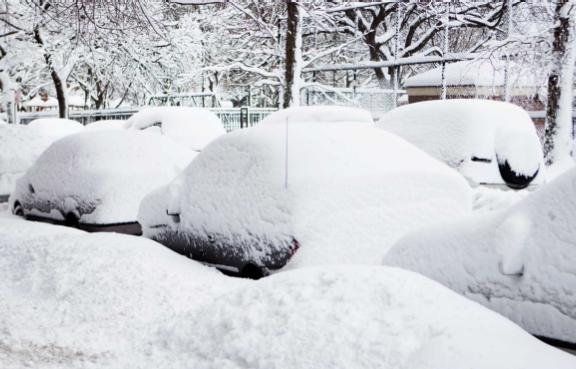 Völlig eingeschneite Autos parkend am Straßenrand im Winter.
