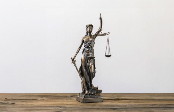 Kleine Statue der Justitia auf einem Schreibtisch.