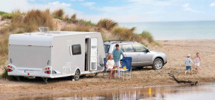 Familie mit Wohnwagen am Strand