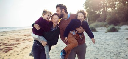 Junge Familie tollt am Strand herum.