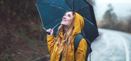 Frau steht mit Regenschirm auf der Straße