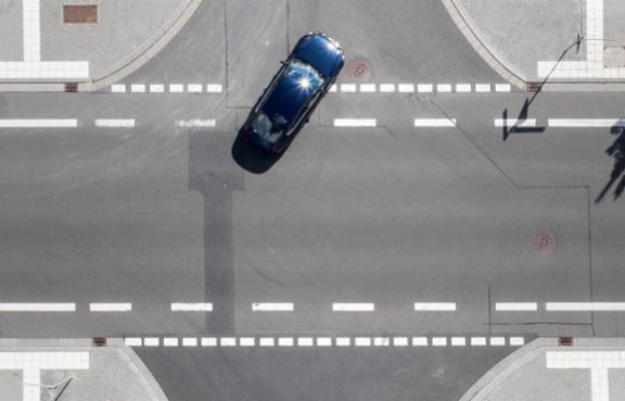 Kreuzung von oben: Ein Auto biegt links ab.