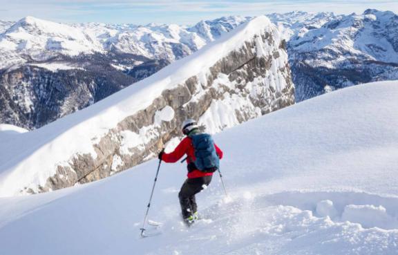 Ein Skifahrer fährt durch Tiefschnee bergab.
