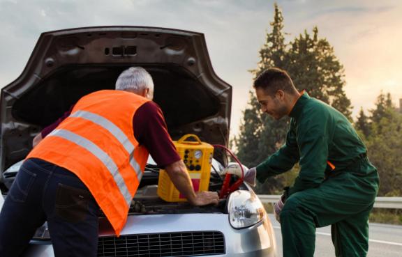 Zwei Pannenhelfer versuchen einem Auto Starthilfe zu geben.