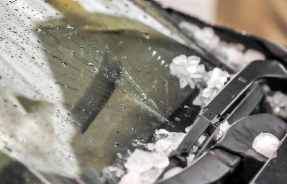 Hagel auf einer gesprungenen Frontscheibe eines Autos.