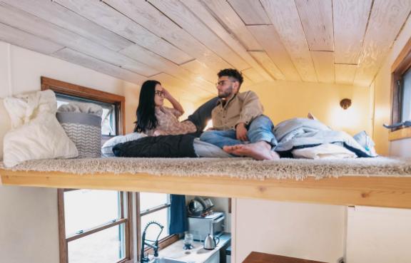 Ein Pärchen liegt im Bett eines Tiny House.