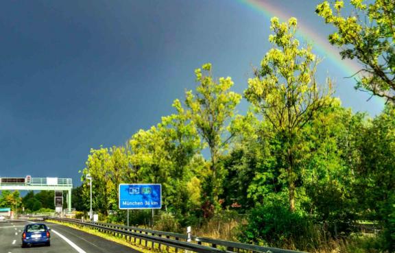 Dunkle Wolken mit einem Regenbogen über einer Autobahn