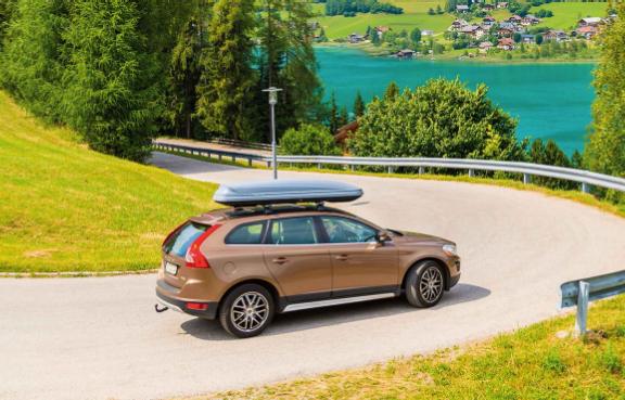 SUV mit Dachbox fährt Serpentinen herunter.