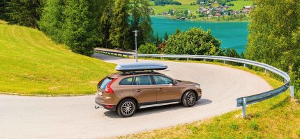 SUV mit Dachbox fährt Serpentinen herunter.