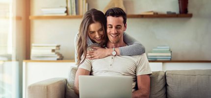 Pärchen sitzt im Wohnzimmer vor dem Laptop