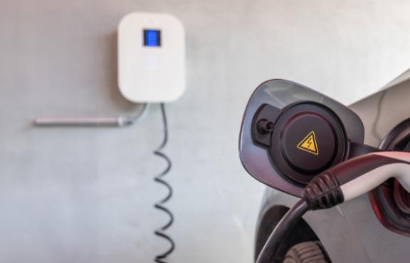 Stecker in einem E-Auto vor einer Wallbox.