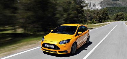 Ein gelbes Auto mit Wechselkennzeichen fährt auf einer Straße.