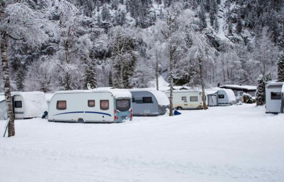 Campingplatz im Winter mit verschneiten Wohnwagen.
