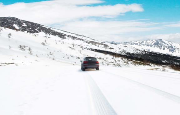 Auto fährt im Winter über eine verschneite Fahrbahn.