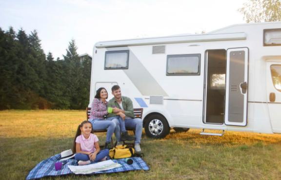 Familie sitzt vor ihrem Wohnmobil