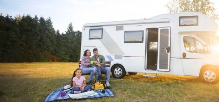 Familie sitzt vor ihrem Wohnmobil