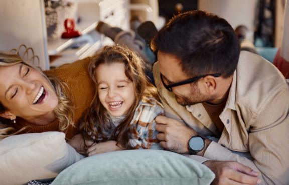 Eltern liegen mit ihrer Tochter in einem Wohnmobil und lachen