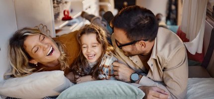 Eltern liegen mit ihrer Tochter in einem Wohnmobil und lachen