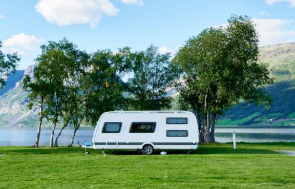 Ein Wohnwagens steht auf einem Campingplatz am See.