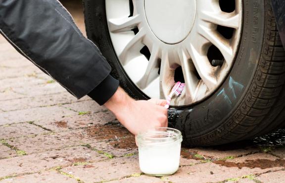 Mann reinigt mit Zahnbürste die Autofelge