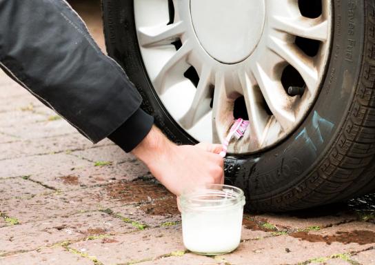 Mann reinigt mit Zahnbürste die Autofelge