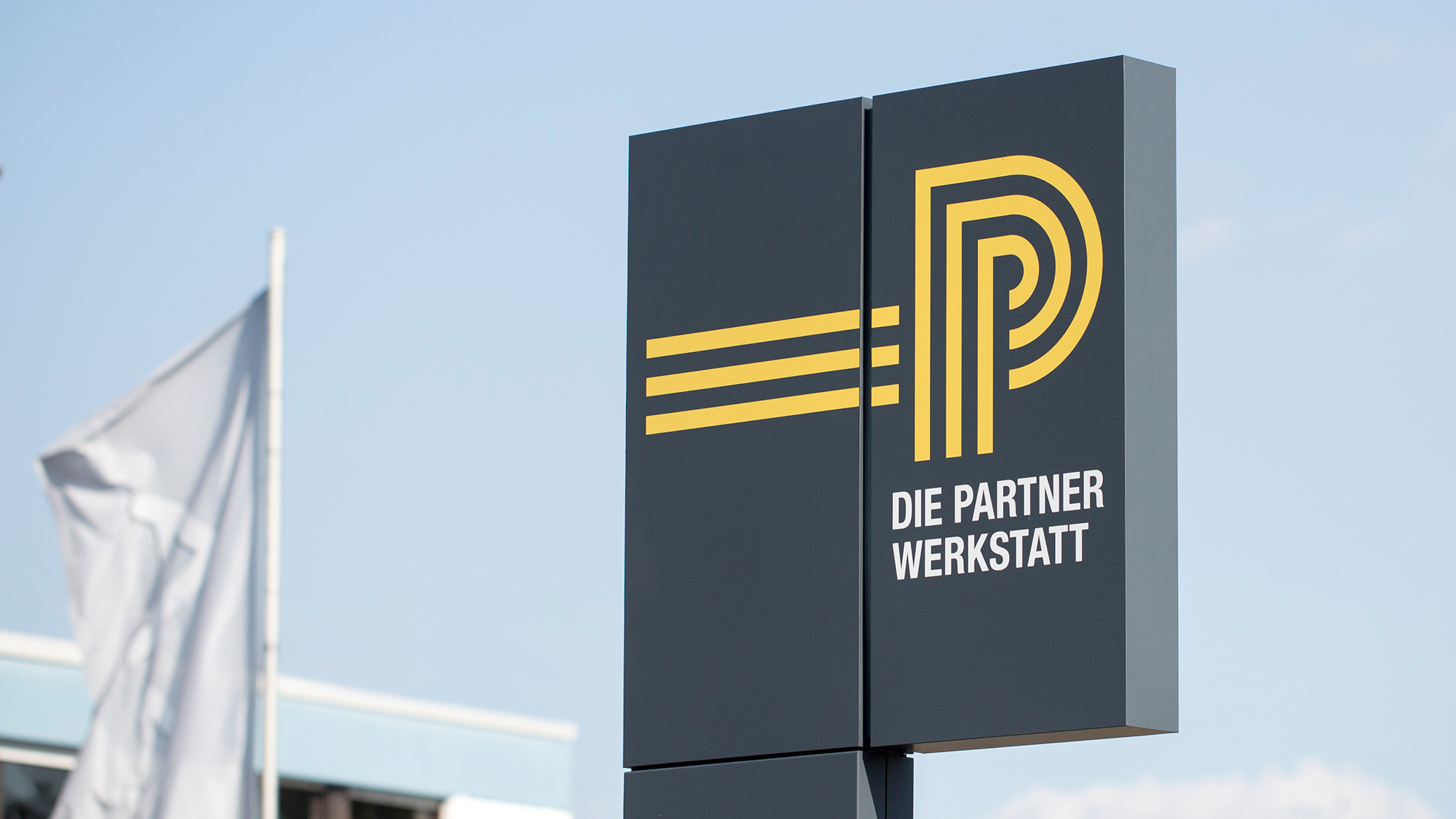 Werbeschild einer HUK Partnerwerkstatt mit der Aufschrift &quot;Die Partnerwerkstatt&quot;