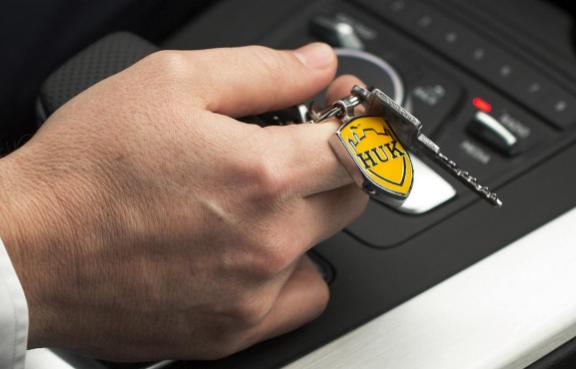 Eine Person hält einen Schlüssel mit einem HUK-COBURG Anhänger in der Hand.