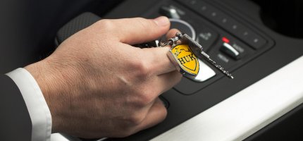 Eine Person hält einen Schlüssel mit einem HUK-COBURG Anhänger in der Hand.