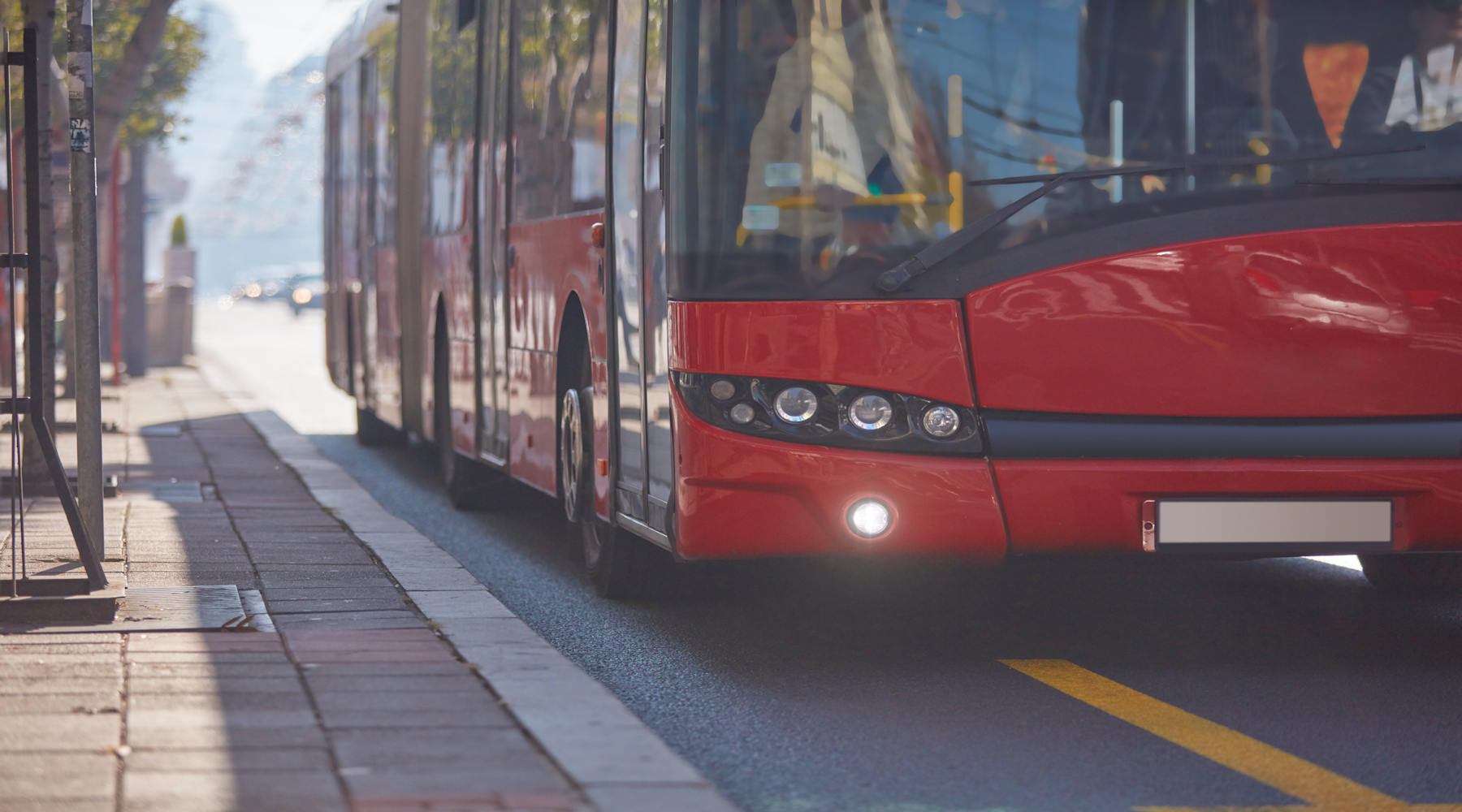 Mehrachsiger Bus an einer Bushaltestelle in der Stadt