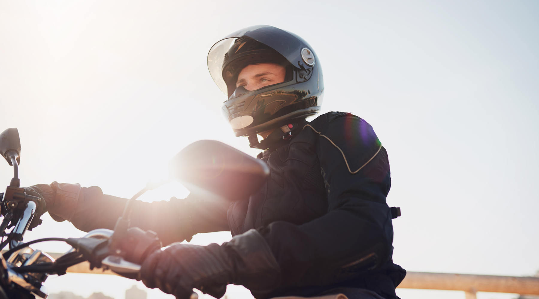 Nahaufnahmen eines Manns auf einem Motorrad mit offenem Helmvisier.