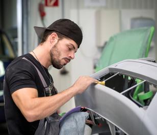 Werkstattmitarbeiter behandelt die Frontpartie eines Autos