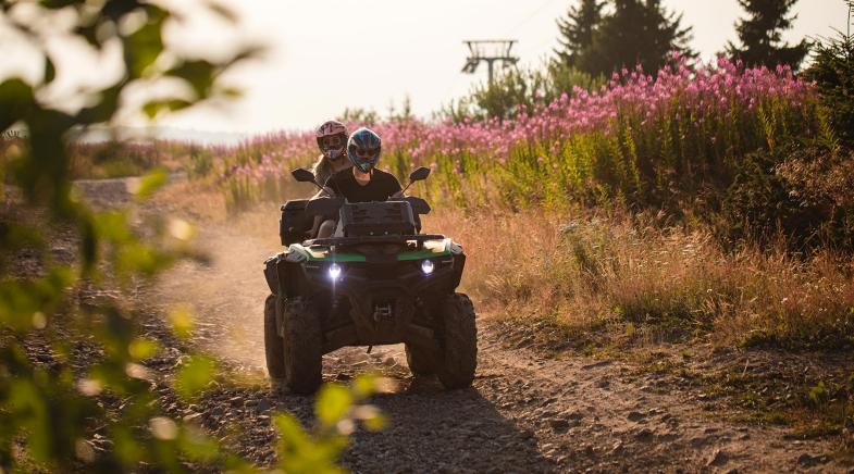 Paar auf Quad fährt über einen Feldweg