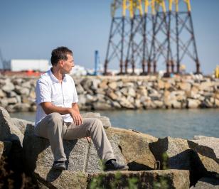 Ein Berater der HUK-COBURG sitzt am Hafen und blickt aufs Wasser.