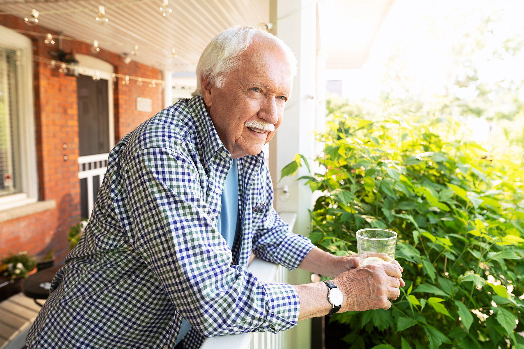 Älterer Herr mit Glas auf der Terrasse