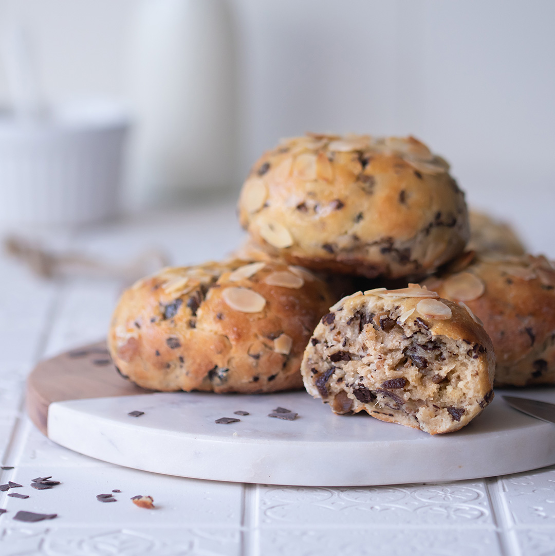 Ein Teller voller Quark-Schokobrötchen. Ein Brötchen ist halbiert. 