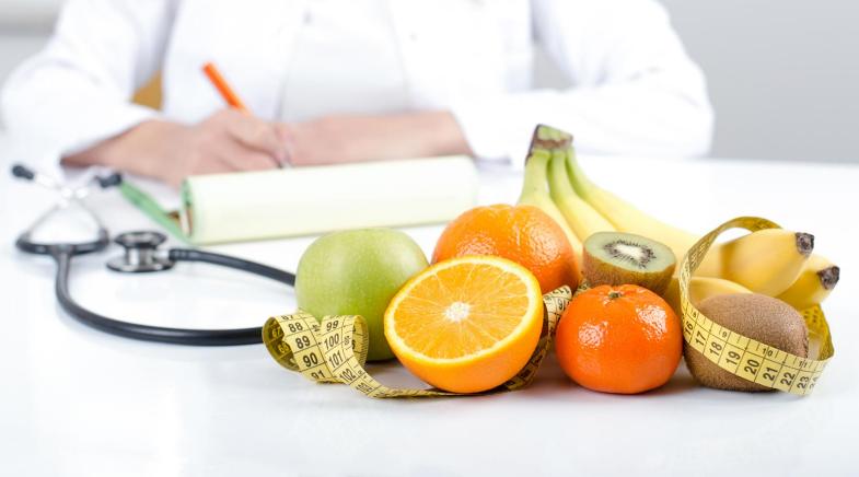 Ärztin sitzt an einem Schreibtisch mit Obst und Zitrusfrüchten.