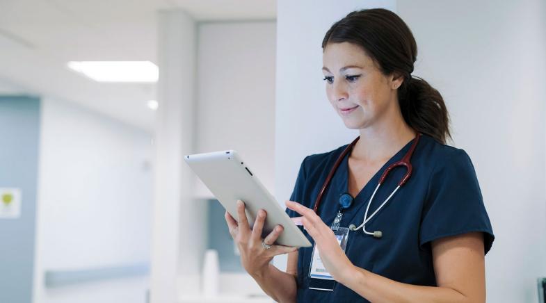 Junge Ärztin schaut im Krankenhaus auf ein Tablet.