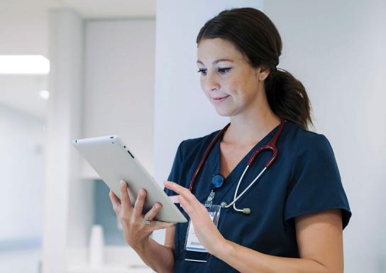 Junge Ärztin schaut im Krankenhaus auf ein Tablet.
