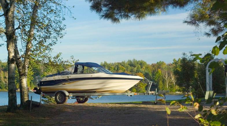 Bootsanhänger ohne Auto steht auf einer Wiese am See.