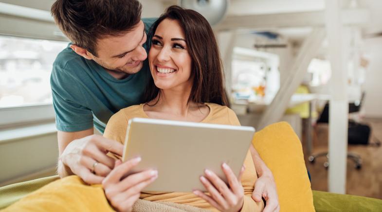 Zwei junge, glückliche Menschen mit Tablet