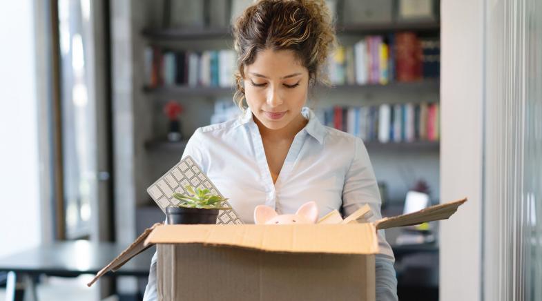 Frau verlässt mit gepackten Sachen das Büro