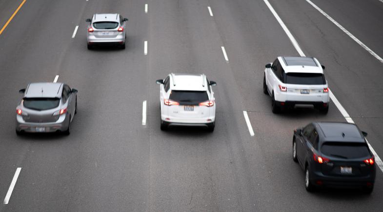 Eine Autobahn mit vier Fahrstreifen und fünf fahrenden Autos.