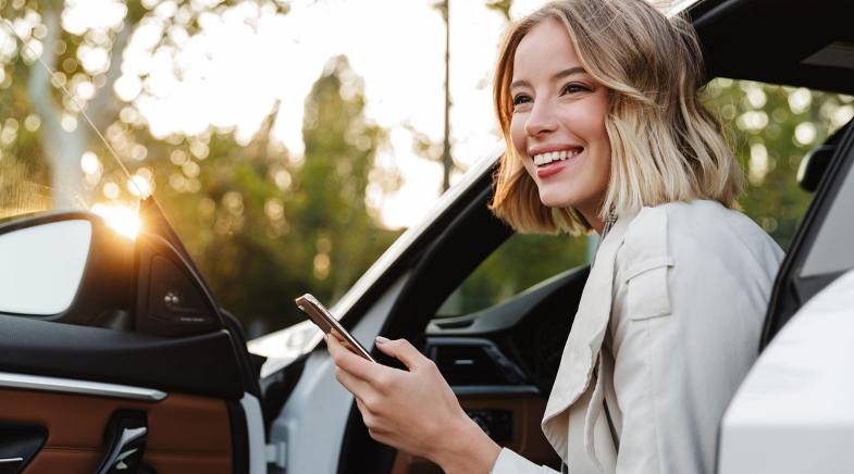 Frau mit Handy in der Hand sitzt im Auto