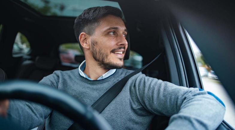 Eine Person sitzt im Auto und schaut aus dem Fenster, während sie den Sicherheitsgurt trägt.