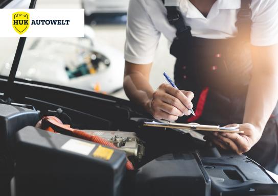 Mechaniker geht an einem Auto eine Checkliste durch. Links oben ist das HUK Autowelt Logo.
