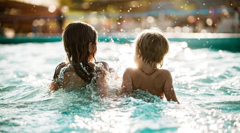 Zwei Kleinkinder im Kinderbecken eines Freibads.